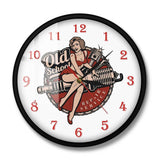 Horloge murale garage vintage avec cadran blanc, chiffres rouges, trois aiguilles, illustration d’une femme pin-up assise sur une bougie de moteur et inscription Old School en arrière-plan. Un design rétro inspiré de l’univers automobile avec cadran acrylique