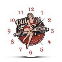Horloge murale garage vintage avec cadran blanc, chiffres rouges, trois aiguilles, illustration d’une femme pin-up assise sur une bougie de moteur et inscription Old School en arrière-plan. Un design rétro inspiré de l’univers automobile.