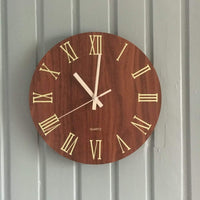 Photo client d'une horloge murale moderne chiffre romain installée sur un mur en lambris gris.