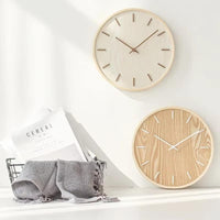 Mise en situation de deux horloges murales en bois naturel clair et foncé, design nordique pour une décoration intérieure tendance.