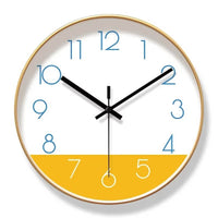 Horloge murale nordique au design scandinave, avec cadran blanc et partie inférieure jaune moutarde. Les aiguilles noires contrastent avec les chiffres bleus. Son contour peut être noir ou doré. Cette horloge murale moderne et élégante apporte une touche chaleureuse et originale à un salon, une chambre ou un bureau doré cadran