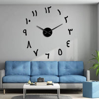 Horloge murale adhésive de couleur noir avec des chiffres orientaux, installée sur un mur gris au-dessus d'un canapé bleu. Ce modèle de décoration murale moderne offre un design épuré et élégant pour habiller votre intérieur.