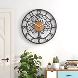 Grande horloge murale design Arbre de Vie en métal et bois accrochée sur un mur blanc au-dessus d'une commode et de plantes
