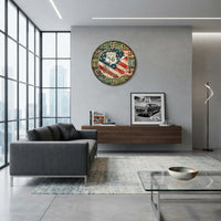 horloge murale américaine au design vintage accrochée bien en vue sur le mur gris d'un salon moderne. L'horloge ronde se distingue par son cadran effet bois patiné affichant le drapeau des États-Unis et le célèbre panneau de la Route 66, créant un contraste saisissant avec l'aménagement contemporain et urbain de la pièce.