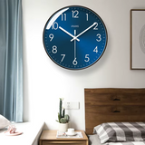 Horloge murale bleue au cadran bleu profond avec douze chiffres blancs et trois aiguilles blanches. Son contour noir souligne son allure contemporaine. Cette horloge au style moderne et épuré convient à une décoration minimaliste dans la chambre.