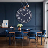 Horloge murale bleue marine ancienne mise en valeur sur un mur terracotta dans un salon avec canapé en velours bleu.