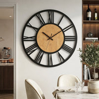 Cette horloge murale en bois et métal de 40 cm avec chiffre romains associe un style industriel et scandinave à une forme ronde et minimaliste, idéale pour salle à manger