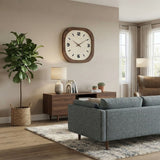 Horloge murale carrée en bois accrochée dans un salon moderne et chaleureux avec canapé bleu et plante verte