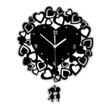 Horloge murale design noir avec un grand cœur central entouré de multiples petits cœurs et un balancier motif couple d'amoureux.