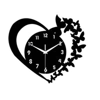 Horloge murale design en forme de cœur noir avec une silhouette d'envol de papillons sur le côté droit.