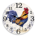 Horloge murale coq français représentant un majestueux coq de profil avec un plumage coloré aux nuances de bleu, orange et rouge sur un cadran blanc cassé aux chiffres originaux de différentes tailles, idéale pour une décoration de cuisine ou d'intérieur au style campagne chic.