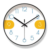 Horloge murale créative nordique avec cadran blanc, chiffres bleus et chiffres 3 et 9 sur fond jaune moutarde. Le cadre noir souligne son design minimaliste et scandinave. Cette horloge moderne associe sobriété et touches colorées pour décorer élégamment un salon, une chambre, un bureau ou une entrée avec une décoration contemporaine.