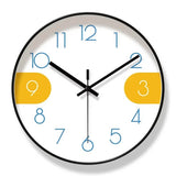 Horloge murale créative nordique avec cadran blanc, chiffres bleus et chiffres 3 et 9 sur fond jaune moutarde. Le cadre noir souligne son design minimaliste et scandinave. Cette horloge moderne associe sobriété et touches colorées pour décorer élégamment un salon, une chambre, un bureau ou une entrée avec une décoration contemporaine.