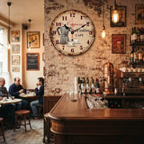 une horloge murale cappuccino vintage rouge et bois veilli pour la cuisine avec une cafetière et deux tasses de café avec écriture family tradition cafe cappucciono installé sur le mur d'un bistro-bar italien