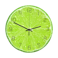 Horloge murale ronde dont le cadran est une image photoréaliste en gros plan d'une tranche de citron vert. Les quartiers de pulpe vert vif et la membrane blanche sont détaillés. Les chiffres arabes noirs et fins (de 1 à 12) sont disposés en cercle. Trois aiguilles noires (heures, minutes, secondes) sont fixées au centre.