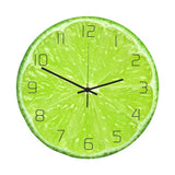 Horloge murale ronde dont le cadran est une image photoréaliste en gros plan d'une tranche de citron vert. Les quartiers de pulpe vert vif et la membrane blanche sont détaillés. Les chiffres arabes noirs et fins (de 1 à 12) sont disposés en cercle. Trois aiguilles noires (heures, minutes, secondes) sont fixées au centre.