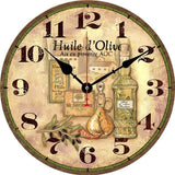 Horloge murale vintage représentant une bouteille d'huile d'olive extra vierge artisanale accompagnée de plusieurs contenants traditionnels. Le cadran affiche l'inscription « Huile d'Olive Aix-en-Provence AOC » avec une branche d'olivier au premier plan et un village provençal en arrière-plan. Les couleurs vertes et brunes rappellent les paysages méditerranéens et les oliveraies du sud de la France. Cette horloge décorative avec deux aiguilles noires et une trotteuse rouge apporte une ambiance authentique à