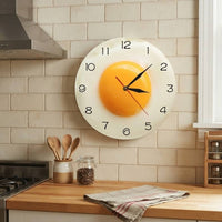 Horloge murale œuf au plat suspendue sur un mur de cuisine moderne avec plan de travail en bois