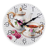 Horloge murale décorative pour cuisine représentant une théière française blanche avec des roses peintes et une tasse assortie à côté. Les poignées dorées apportent une touche élégante, tandis que quelques framboises roses décorent le côté de la composition. Le cadran blanc cassé vintage est entouré de 12 chiffres noirs et de deux aiguilles noires, créant une ambiance romantique et chaleureuse inspirée des salons de thé français. Cette horloge murale théière s’intègre parfaitement dans une cuisine rétro, ch
