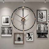 Grande horloge murale design salon en métal noir et bois suspendue au milieu d'un mur de cadres photos