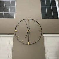 Horloge murale decorative salon géante style industriel installée sur un mur de salon à haute hauteur sous plafond.