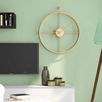 Horloge murale dorée design fixée sur un mur vert menthe moderne dans un salon. La finition dorée contraste parfaitement avec la teinte pastel pour un rendu frais et stylé