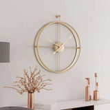 Horloge murale dorée design suspendue au-dessus d'une console élégante en arrière-plan. L'association avec un vase fleuri et des bougeoirs dorés crée une décoration d'intérieur raffinée.