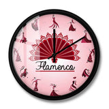 Horloge murale flamenco avec cadran rosé en dégradé. Chaque heure est représentée par une élégante danseuse dans une position différente de danse flamenco. Le mot « Flamenco » apparaît sur le cadran. Les aiguilles noires complètent ce design inspiré de la culture espagnole et de la passion de la danse.