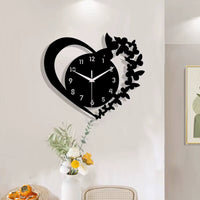 Horloge murale design en forme de cœur noir avec une silhouette d'envol de papillons sur le côté droit dans la salle