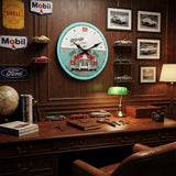 Horloge murale vintage Garage automobile "SERRURE & REPAIR" accrochée au mur d'un bureau d'amateur de voitures, au-dessus d'un bureau en bois avec des modèles réduits et des plaques émaillées rétro (Mobil, Ford, Shell).