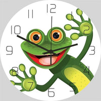 Horloge murale grenouille verte sur fond blanc, avec une grenouille souriante au centre du cadran, les bras et les pattes écartés, entourée de chiffres noirs.Diamètre 30 cm et l'horloge grenouille est parfaite pour une chambre enfant.