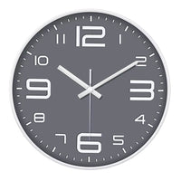 Une horloge murale grise contemporaine pour cuisine. Ce modèle arbore de grands chiffres numériques stylisés (12, 3, 6, 9 agrandis), des index en forme de bâtonnets blancs et un cadran gris foncé épuré.