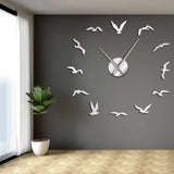 Grande horloge géante argentée effet miroir motif oiseaux en vol décorant un mur de chambre gris anthracite
