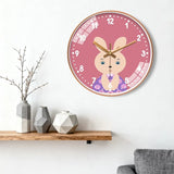 Horloge murale lapin rose pour chambre enfant, avec un petit lapin souriant et légèrement timide, des chiffres blancs et un joli fond rose. Cette horloge murale lapin apporte une touche douce et adorable à la décoration, idéale pour les enfants et les amoureux des lapins pour la chambre enfant