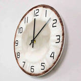 Horloge murale en forme de moitié de noix de coco avec une coque marron et un centre blanc rappelant la chair du fruit, décoration exotique.-side
