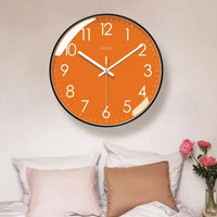 Horloge murale orange moderne avec cadran orange, contour noir, chiffres blancs et aiguilles blanches. Les minutes sont indiquées par des points blancs autour du cadran. Son design épuré et coloré convient parfaitement au salon, à la chambre ou à la cuisine pour apporter une touche chaleureuse 