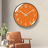 Horloge murale orange moderne avec cadran orange, contour noir, chiffres blancs et aiguilles blanches. Les minutes sont indiquées par des points blancs autour du cadran. Son design épuré et coloré convient parfaitement au salon, à la chambre ou à la cuisine pour apporter une touche chaleureuse et contemporaine dans le salon