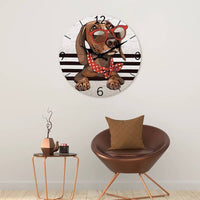 Horloge murale teckel décorative idéale pour un salon, représentant un adorable chien couché avec la tête posée sur ses deux pattes avant. Le teckel porte de grandes lunettes rouges et un foulard rouge à pois blancs qui lui donnent un style original et attachant. Son regard doux et expressif semble vous écouter et créer une véritable sensation de complicité. Le cadran blanc gris clair apporte une touche élégante et moderne tandis que les quatre bandes noires ajoutent un effet design