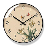 Horloge murale design style asiatique avec cadre noir. Cadran effet toile beige orné d'une illustration d'inspiration japonaise avec des jonquilles jaunes, deux papillons orange et un sceau rouge traditionnel.