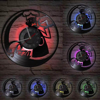 orloge murale en vinyle sculpté représentant la silhouette d'un chef pizzaiolo. Ses LED intégrées diffusent une lumière colorée sur le mur arrière.