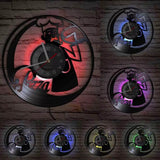 orloge murale en vinyle sculpté représentant la silhouette d'un chef pizzaiolo. Ses LED intégrées diffusent une lumière colorée sur le mur arrière.