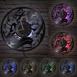 Horloge murale LED en vinyle sculpté illustrant un barbier au travail et l'inscription In Barber We Trust avec lumière multicolore.