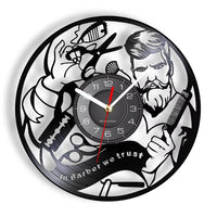 Horloge murale en disque vinyle illustrant un barbier avec ciseaux, peigne, lame de rasoir et l'inscription In Barber We Trust pour barber shop.