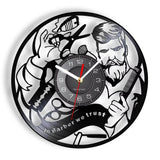Horloge murale en disque vinyle illustrant un barbier avec ciseaux, peigne, lame de rasoir et l'inscription In Barber We Trust pour barber shop.
