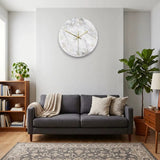 Horloge murale effet marbre gris et blanc accrochée au-dessus d'un canapé gris dans un salon au style scandinave.