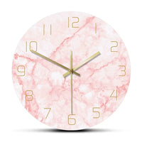 Horloge murale ronde motif marbre rose pastel et blanc avec détails métalliques dorés.
