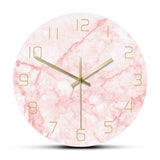 Horloge murale ronde motif marbre rose pastel et blanc avec détails métalliques dorés.