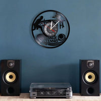 Horloge murale ronde en vinyle de 30 cm représentant deux joueurs de tennis de table en pleine partie, avec raquettes et balle. Un modèle décoratif au style rétro, idéal pour une chambre, une salle de jeux ou l’espace d’un passionné de tennis de table noir.