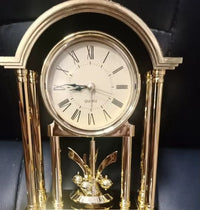 Véritable mini horloge dorée à pendule rotatif, détail du cadran à chiffres romains et mouvement quartz de précision.