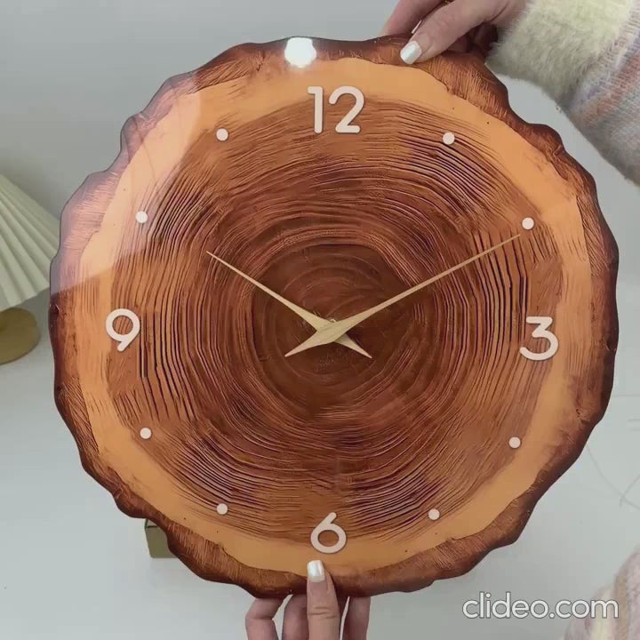 Vidéo démonstrative de l'horloge murale en style bois naturel. La vidéo présente d'abord de près la face avant de l'horloge avec son cadran texturé en forme de rondin de bois, ses chiffres blancs et ses aiguilles dorées. Elle pivote ensuite pour montrer le panneau arrière en plastique de couleur sombre et ses finitions. Enfin, un zoom est réalisé sur le mécanisme à quartz silencieux et l'emplacement destiné aux piles, accompagné des instructions d'utilisation